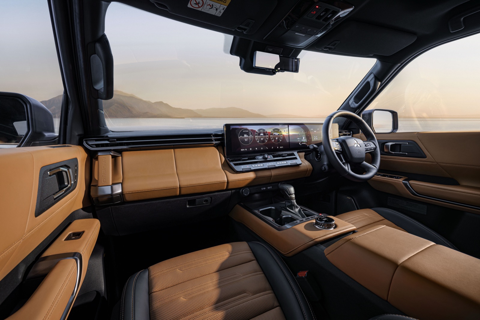 Interior of the new Mitsubishi Pajero showing tan leather seats, a horizontal dashboard and a wide landscape touchscreen in a right-hand-drive layout.